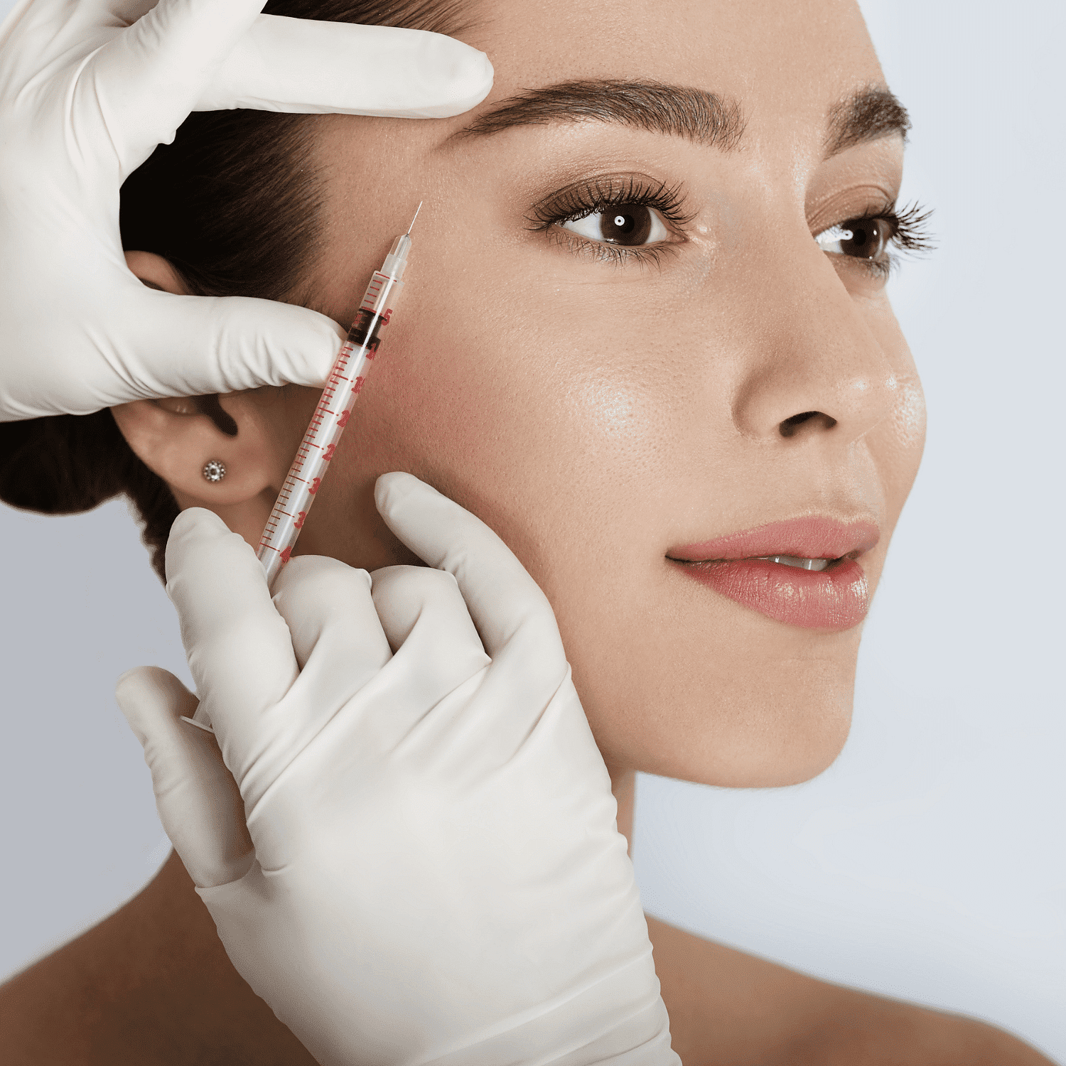 Cosmetic injection near a woman's eye by gloved hands.